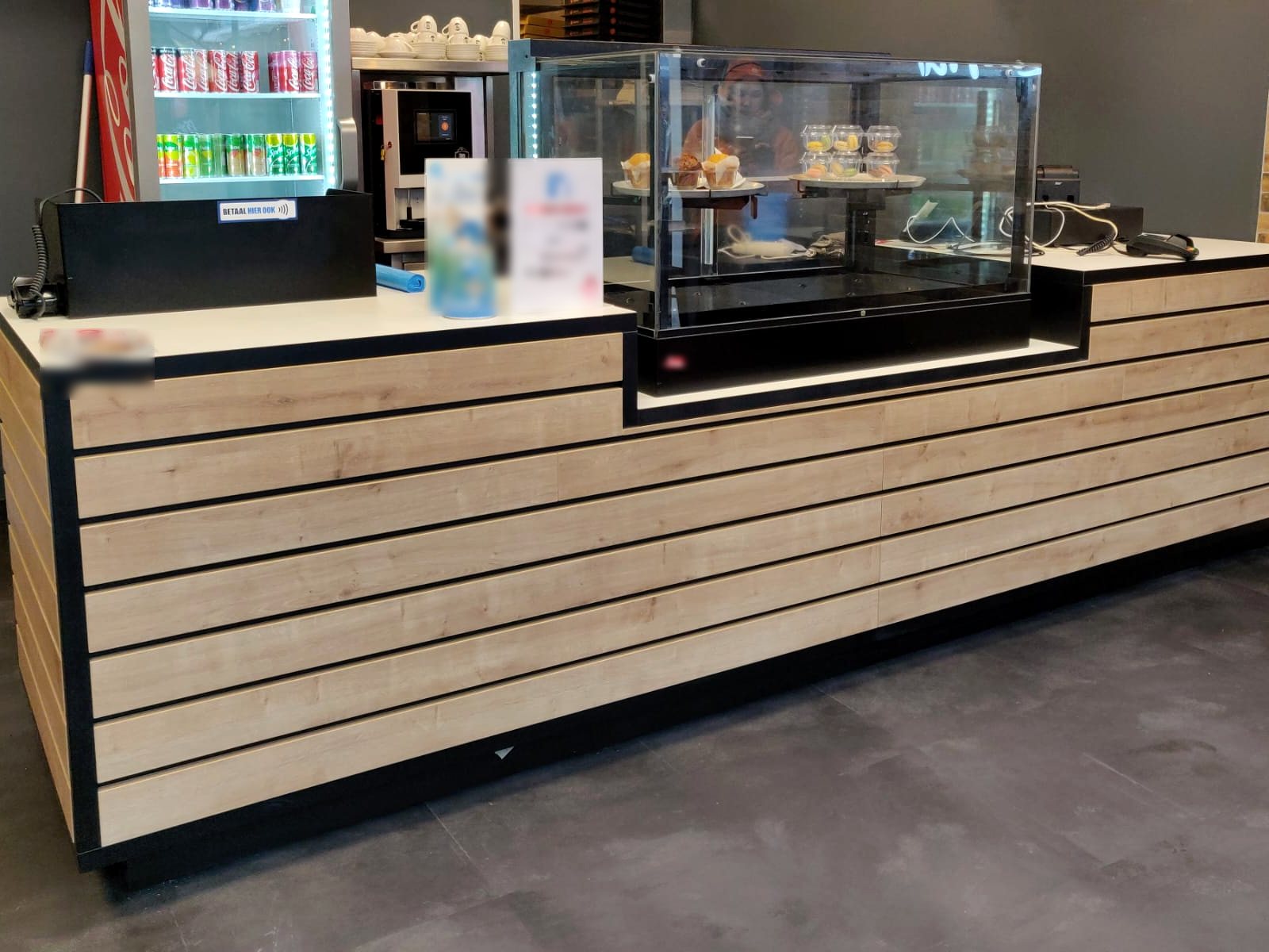 Balie op maat met houten lamellen en zwarte randen in een afhaalrestaurant