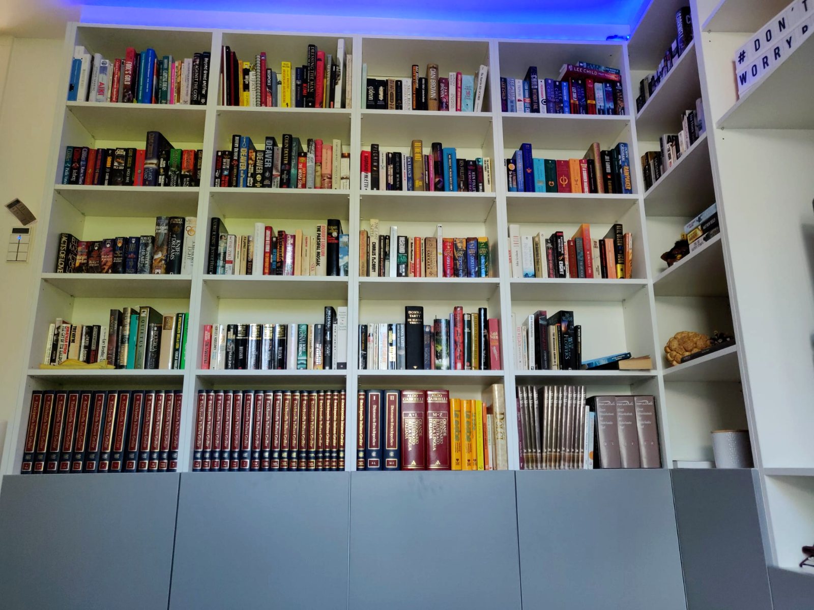 Witte boekenkasten tot aan het plafond met grijze onderkasten