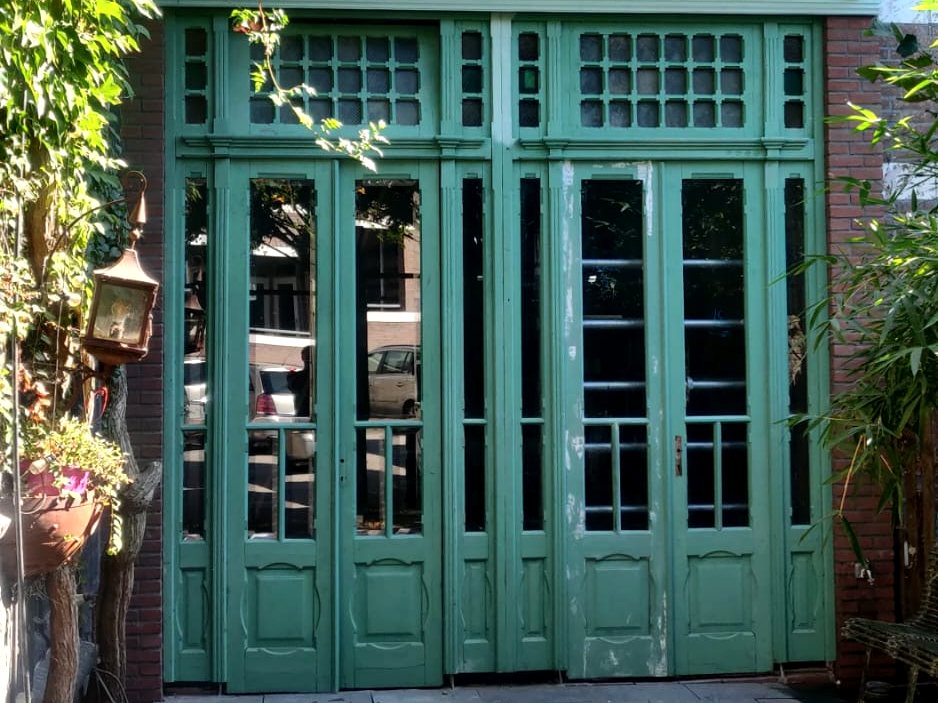 Groene houten pui met glas-in-loodbovenlichten aan de tuinkant